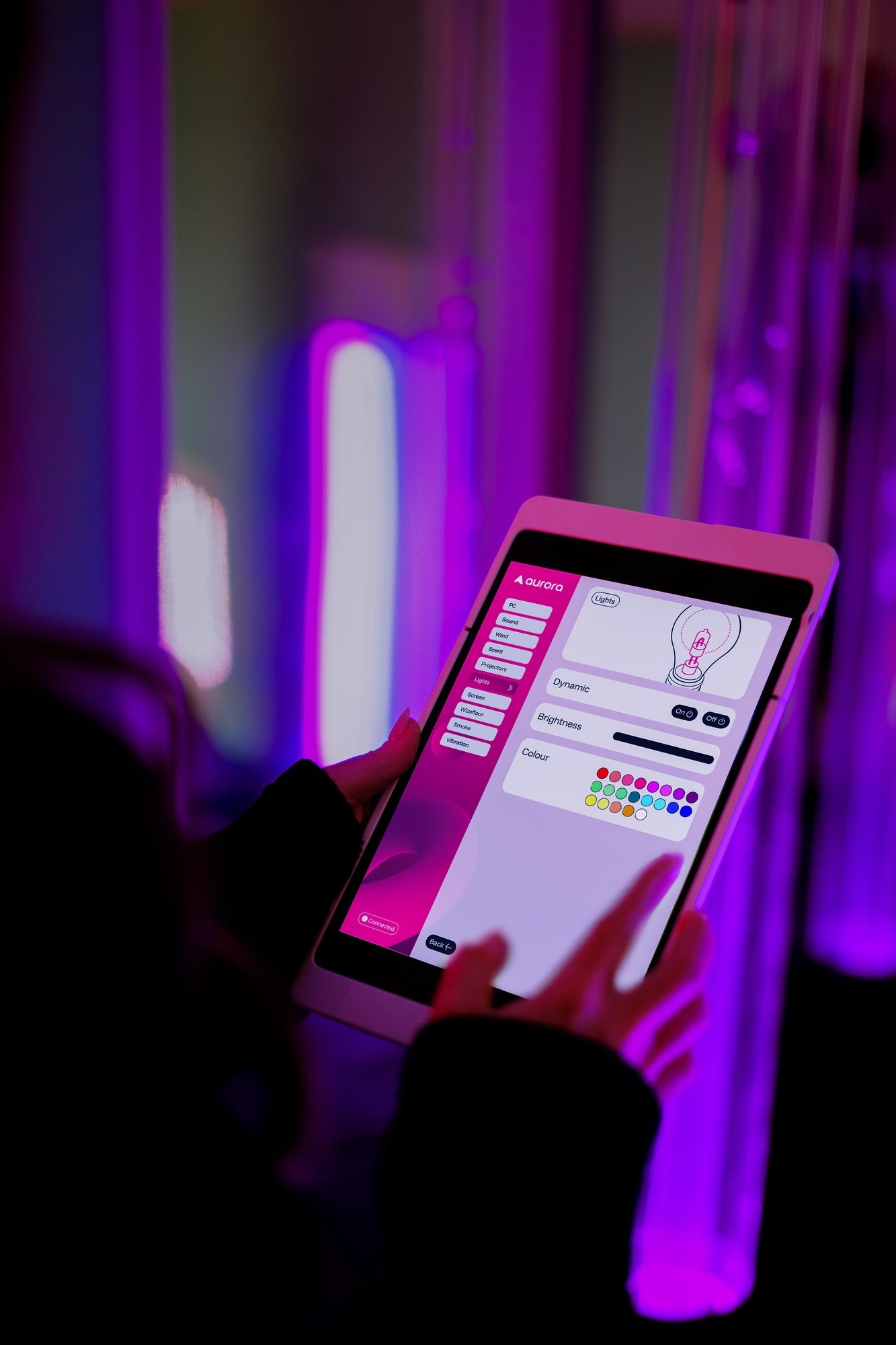 person holding a tablet using the aurora console app to control the room lighting