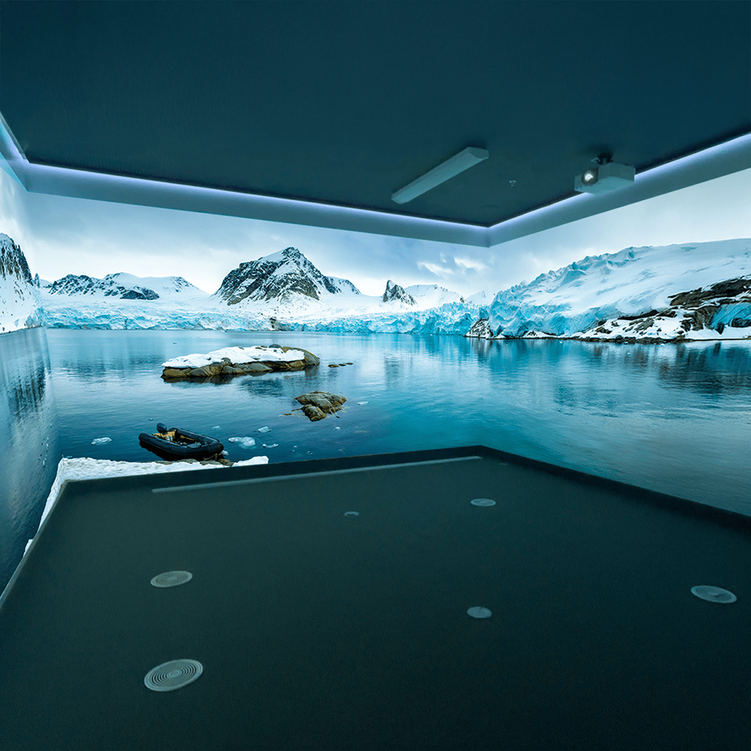 A room with panoramic walls displaying a serene Arctic landscape, featuring snow-covered mountains, a calm icy lake, and an inflatable boat. The scene evokes tranquility.