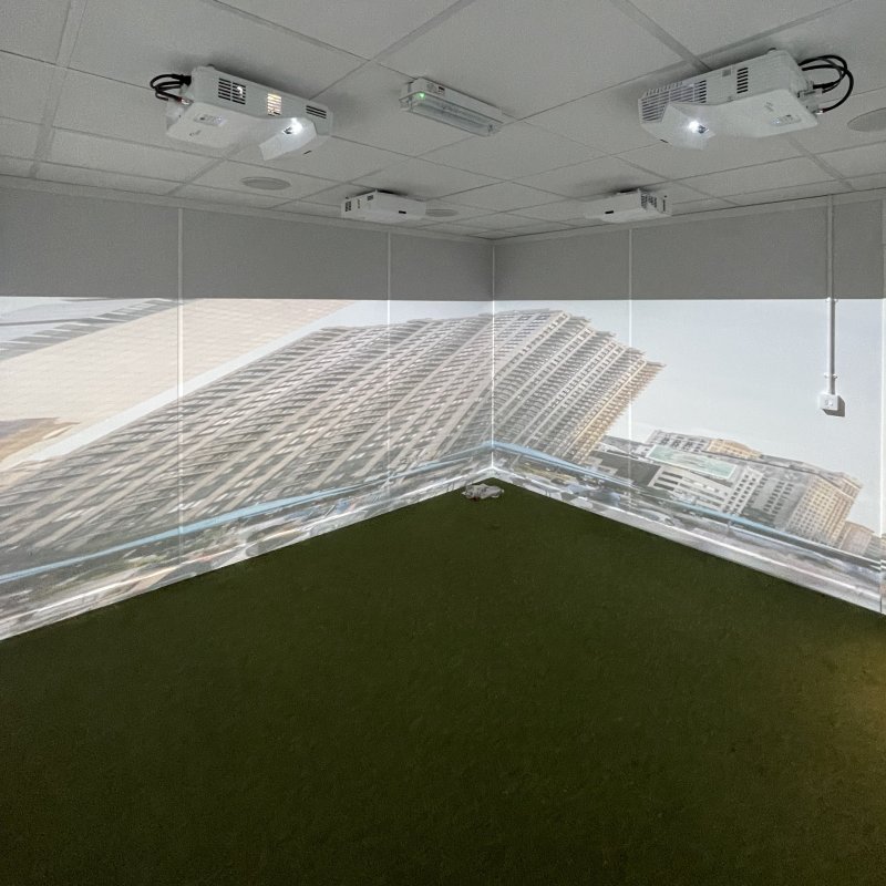 Immersive projection room with ceiling-mounted projectors displaying city skyscrapers, creating a futuristic mood.
